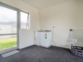 A laundry room with washing machine and drying rack at Sweet As on Aquila - Whitianga Holiday Home