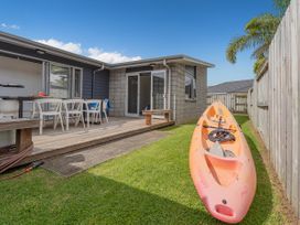 A patio area with a kayak and outdoor furniture at Sweet As on Aquila - Whitianga Holiday Home