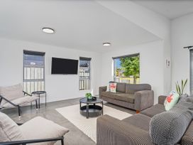A living room with a sofa, armchair, coffee table, and television at Sweet As on Aquila - Whitianga