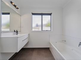 A bathroom with a mirror, sink, bathtub, and window at Sweet As on Aquila - Whitianga