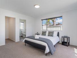 A bedroom with a bed and nightstand at Sweet As on Aquila - Whitianga