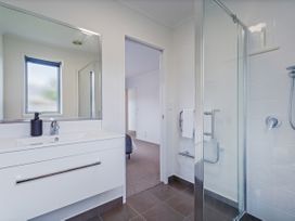 A bathroom with a sink, mirror and shower at Sweet As on Aquila - Whitianga Holiday Home