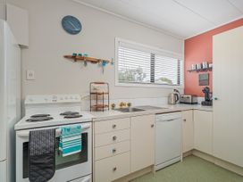 A kitchen with an oven, dishwasher, and sink at The Schieck Shack - Whitianga