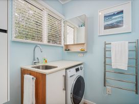 A laundry room with a washing machine and sink at The Schieck Shack - Whitianga