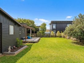 A garden with a house and deck at The Schieck Shack - Whitianga