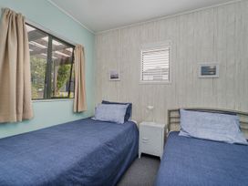 A bedroom with two beds and a window at The Schieck Shack - Whitianga