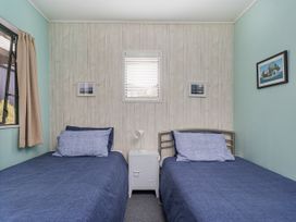 A bedroom with two beds and a window at The Schieck Shack - Whitianga