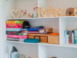 A shelf with games, books, and decorative items at The Schieck Shack - Whitianga