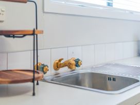 A sink with faucet and shelf in The Schieck Shack - Whitianga