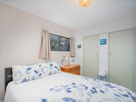 A bedroom with a bed and window at The Schieck Shack - Whitianga Holiday Home