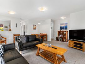 A living room with a sofa, coffee table, and television at Moana - Onehunga Holiday Home in Auckland