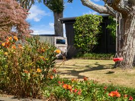 A garden with flowers and a swing at Moana - Onehunga Holiday Home Auckland