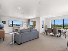 A living room with a sofa and dining table at Riverside Retreat - Waipu Holiday Home in Waipu