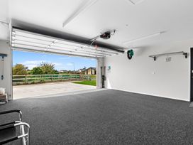 A garage with an open door and tools on the wall at Riverside Retreat - Waipu