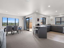 A kitchen with a dining area and windows at Riverside Retreat - Waipu