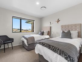 A bedroom with two beds and a chair at Riverside Retreat - Waipu Holiday Home