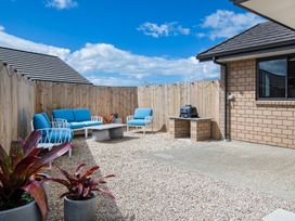 An outdoor seating area with a sofa, table, and barbecue at Riverside Retreat - Waipu