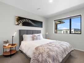 A bedroom with a bed, bedside table, and a window at Riverside Retreat - Waipu Holiday Home