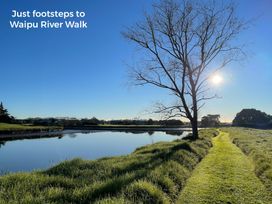 A river with a path and trees at Riverside Retreat - Waipu Holiday Home Waipu