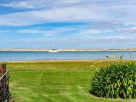 A view of a sailboat on water with grass and plants in the foreground at Mangawhai Marvel - Mangawhai Heads