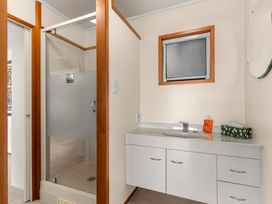 A bathroom with a shower, sink, and mirror at Mangawhai Marvel - Mangawhai Heads
