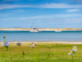 Two boats on the water with grass and flowers in the foreground at Mangawhai Marvel - Mangawhai Heads
