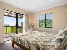 A bedroom with a bed and a view of a patio at Bayview Cottage - Whakamarama