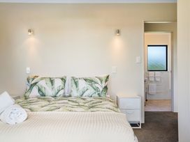 A bedroom with a bed and adjoining bathroom at Bayview Cottage - Whakamarama