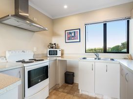 A kitchen with a stove and microwave at Bayview Cottage - Whakamarama