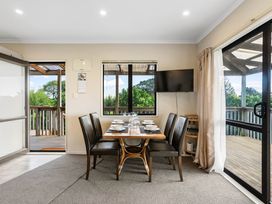 A dining room with a table and chairs at Bayview Cottage - Whakamarama
