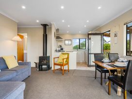 A living room with a dining area and kitchen at Bayview Cottage - Whakamarama