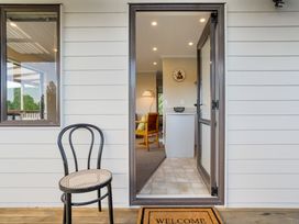 An entryway with a chair and view of a living room at Bayview Cottage - Whakamarama