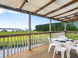 An outdoor area with a table and chairs overlooking a grassy field at Bayview Cottage - Whakamarama