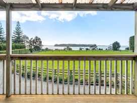 A view from a deck showing grass and water at Bayview Cottage - Whakamarama
