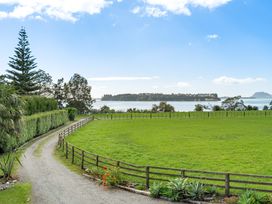 A view of grass field and water at Bayview Cottage - Whakamarama