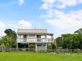 A house with a balcony and garden at Bayview Cottage - Whakamarama Holiday Home in Whakamarama