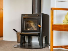 A wood stove with a chimney in a living room at Bayview Cottage - Whakamarama