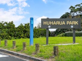 A park sign at Huharua Park with signage and grassy area