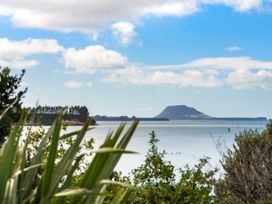 A view of the ocean with a mountain and trees at Bayview Cottage - Whakamarama Holiday Home, Whakamarama