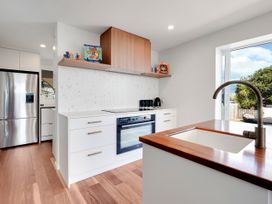 A kitchen with a stove, refrigerator, and sink at Raglan Holiday Home