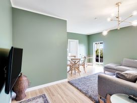 A living room with a television and dining table at Raglan Holiday Home