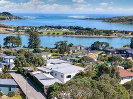 A view of houses and water with trees in the background at Raglan Holiday Home
