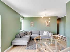 A living room with a sofa and dining table at Raglan Holiday Home