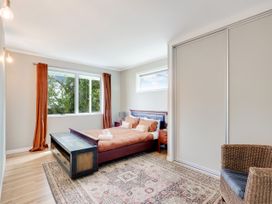 A bedroom with a bed and windows at Raglan Holiday Home