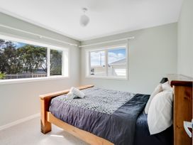 A bedroom with a bed and windows at Raglan Holiday Home 