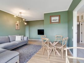 A living room with a sofa and dining area at Raglan Holiday Home