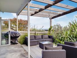 An outdoor seating area with furniture and a grill at Raglan Holiday Home