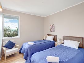 A bedroom with two beds and a chair at Raglan Holiday Home