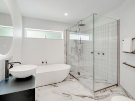 A bathroom with a bathtub and walk-in shower at Raglan Holiday Home