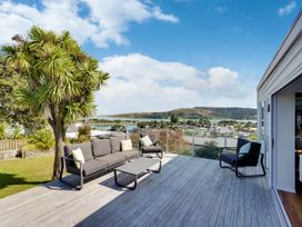 An outdoor area with a sofa and coffee table overlooking a landscape at Raglan Holiday Home 